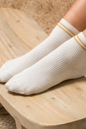 Chaussettes Ginette en coton bio écru, hauteur 10,5 cm, avec deux bandes dorées pailletées et broderie Suny sous le pied
