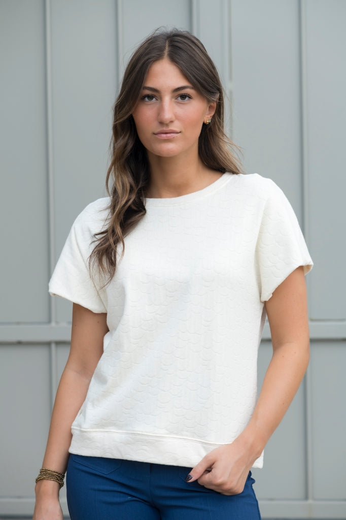 Sweat Gigi en éponge bouclette écru, coupe large et moderne, manches courtes tombantes, porté avec un jean