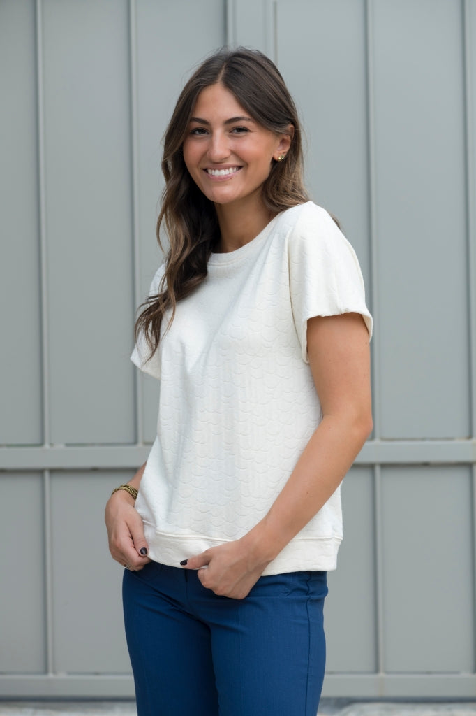 Sweat Gigi en éponge bouclette écru, coupe large et moderne, manches courtes tombantes, porté avec un jean