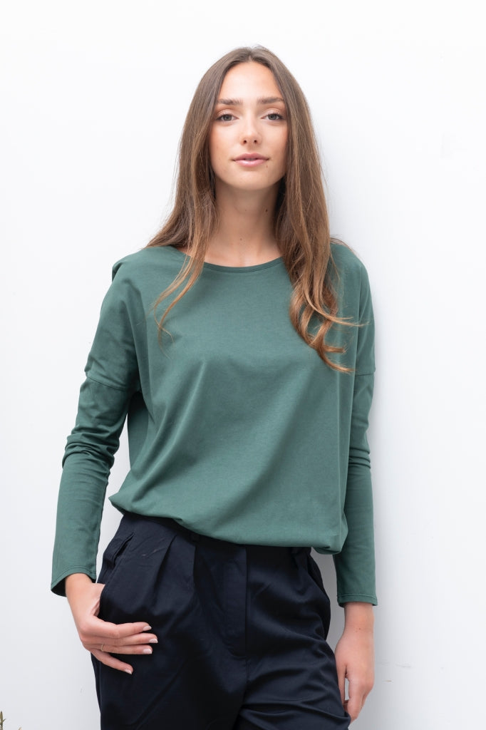 Tee-shirt à manches longues Extra Suny en coton bio vert d’hiver, porté avec un pantalon bleu marine